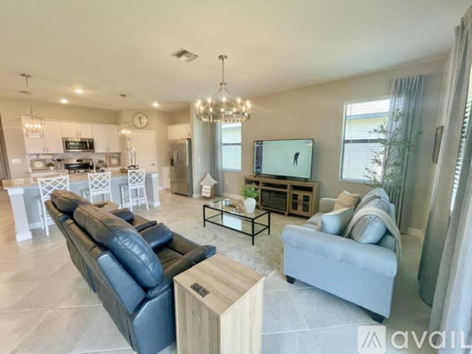 A spacious living room with a black leather sofa and a wooden coffee table.