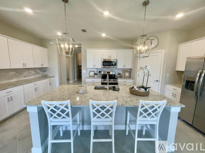 A kitchen with a large island and white chairs.