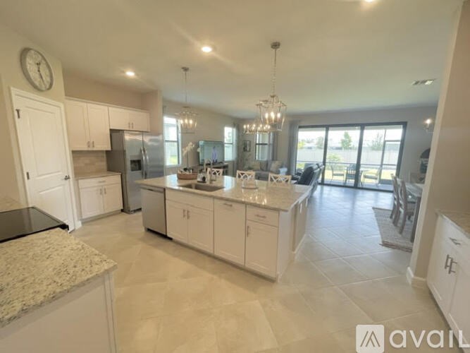 A spacious kitchen with white cabinets and a marble countertop.