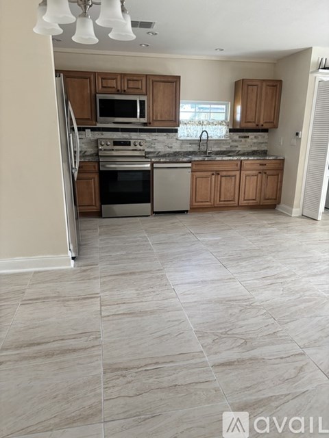 A kitchen with tile flooring and wooden cabinets.