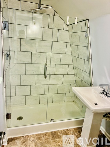 A white sink is in front of a glass shower stall.