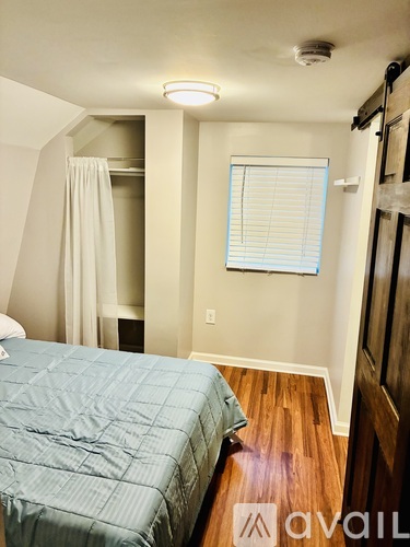 A bedroom with a bed and a window with blinds.
