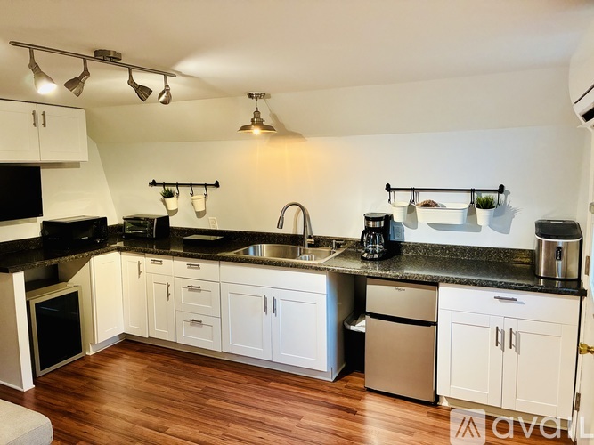A kitchen with white cabinets and black countertops.