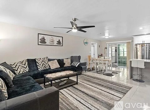 A living room with a black couch and a rug.