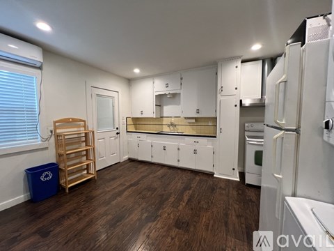 A kitchen with white cabinets and a wooden floor.