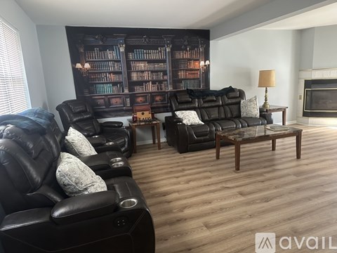 A living room with black leather furniture and a bookshelf filled with books.