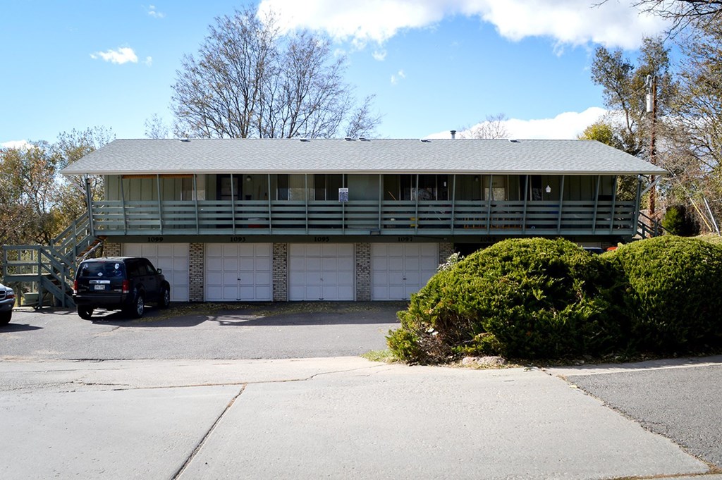 A green house with a car parked in front.
