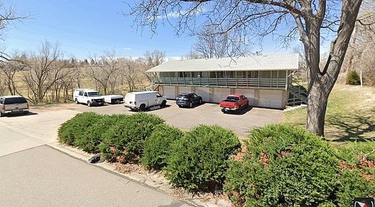 A parking lot with a building and cars.