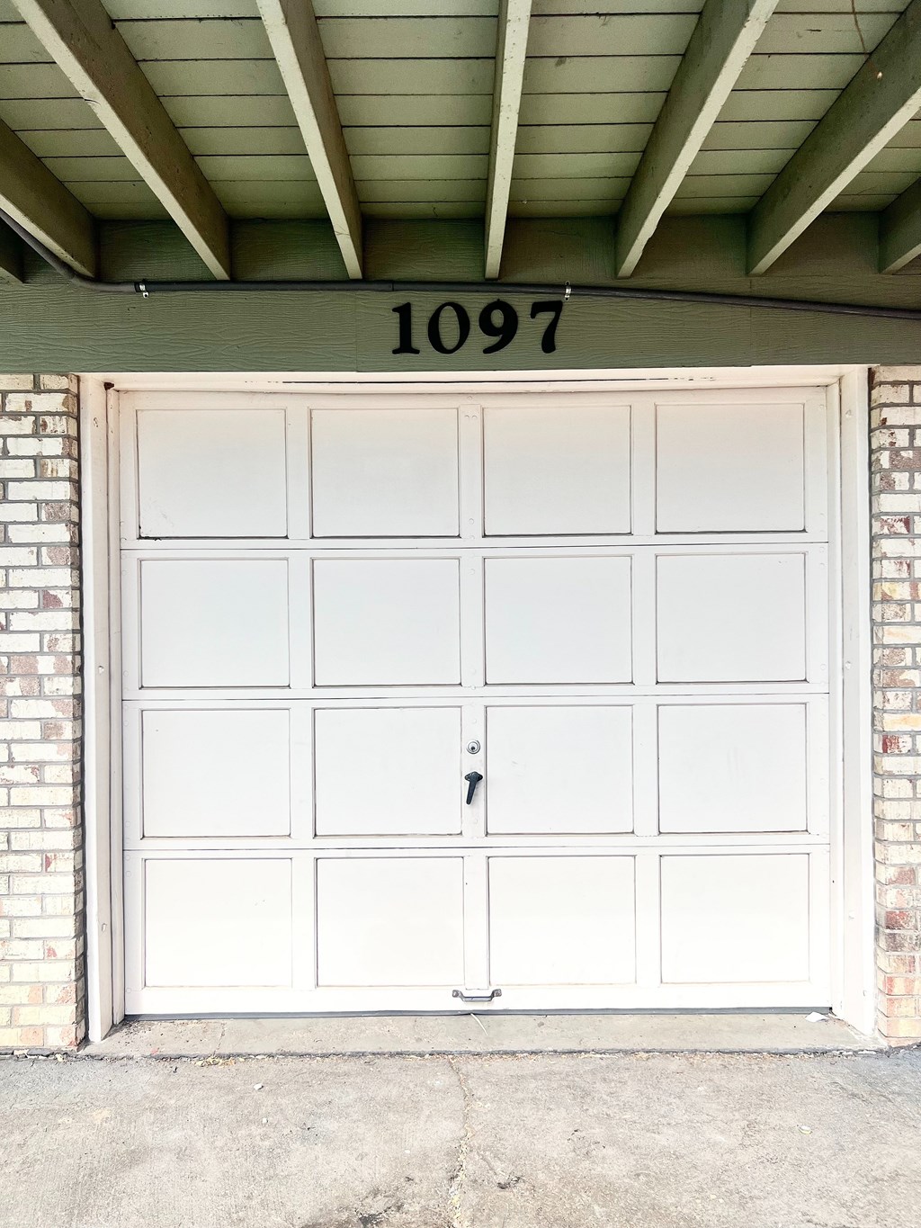 A white garage door with a black number 1097 above it.