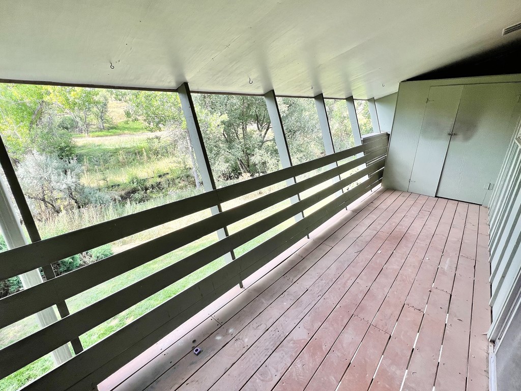 A wooden deck with a view of trees and grass.