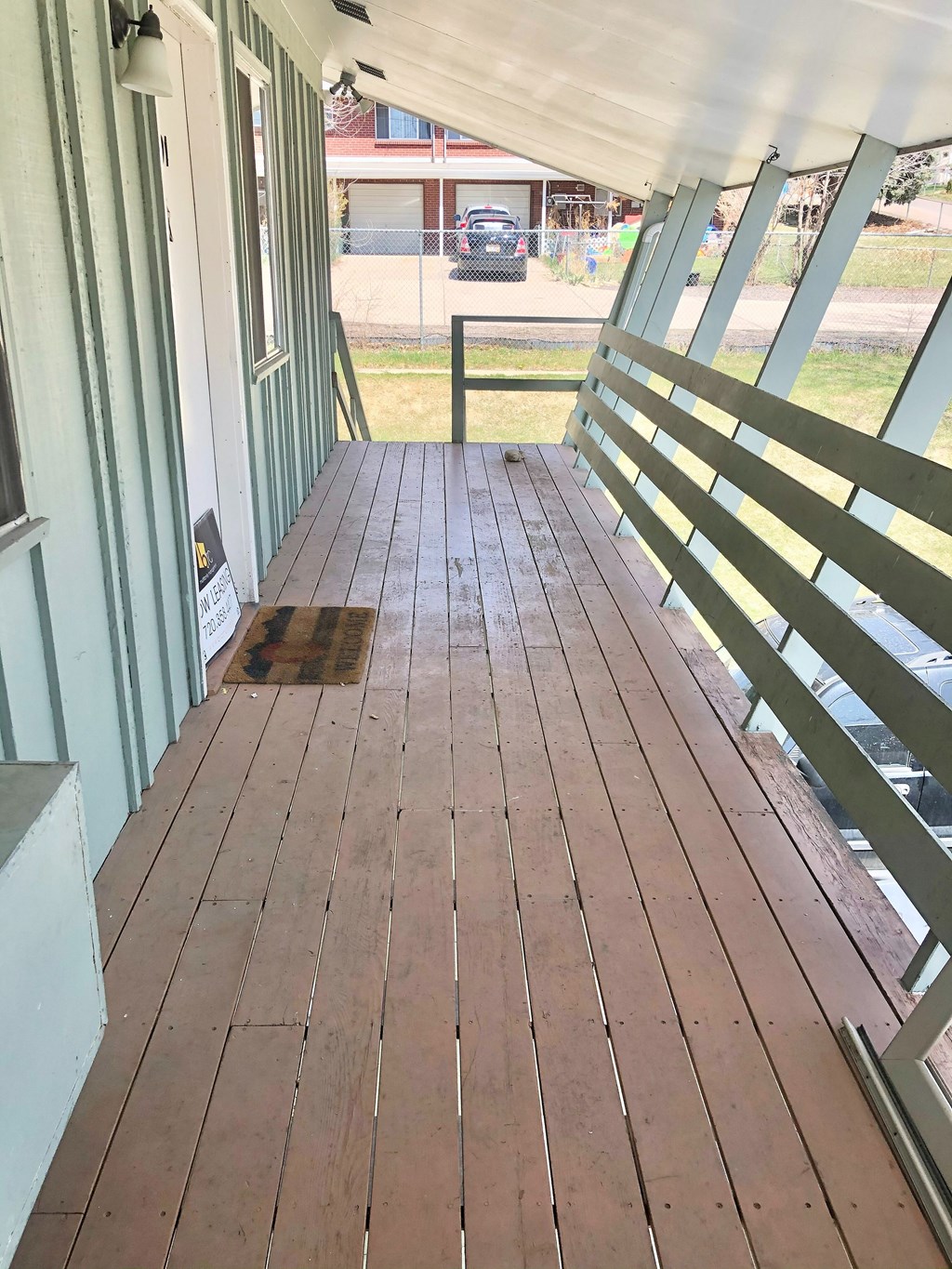 A wooden deck with a white railing and a white wall.