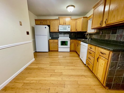 A kitchen with wooden cabinets and a white refrigerator.