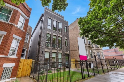 A row of houses with a black fence in front.
