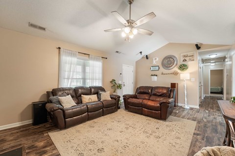 A living room with two brown leather couches and a rug.