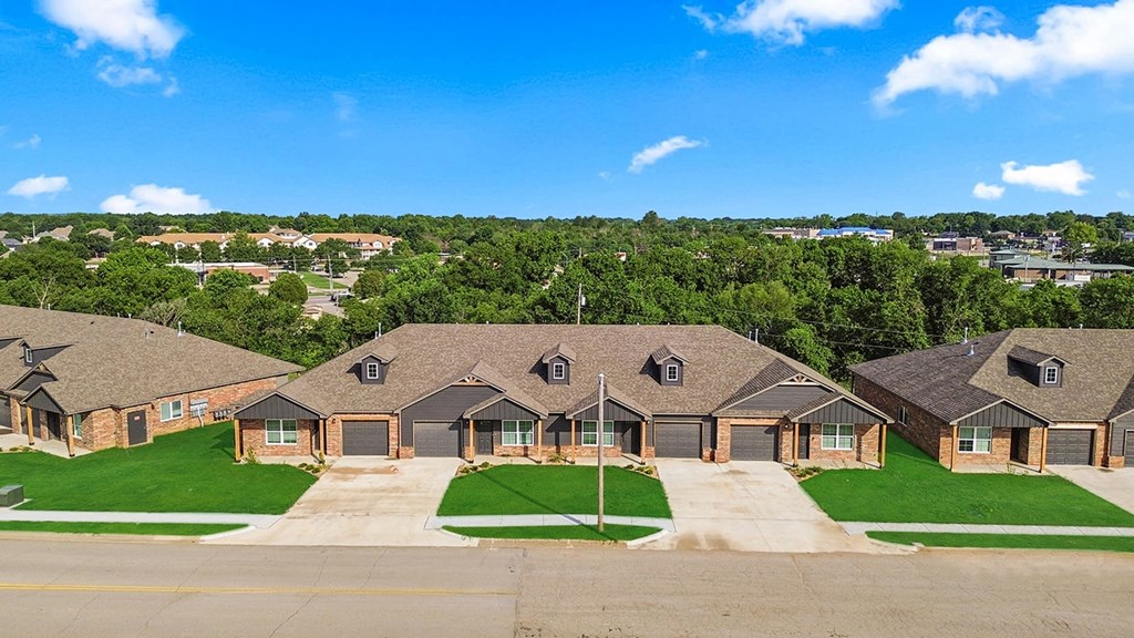 A row of houses with green lawns and trees in the background.