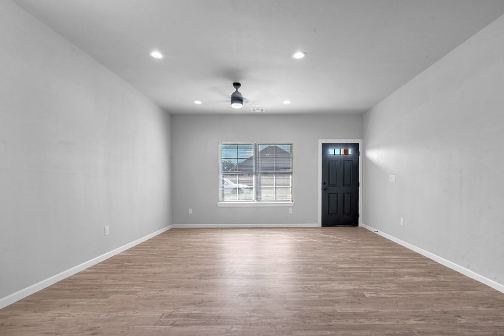 A room with a black door and a window with blinds.