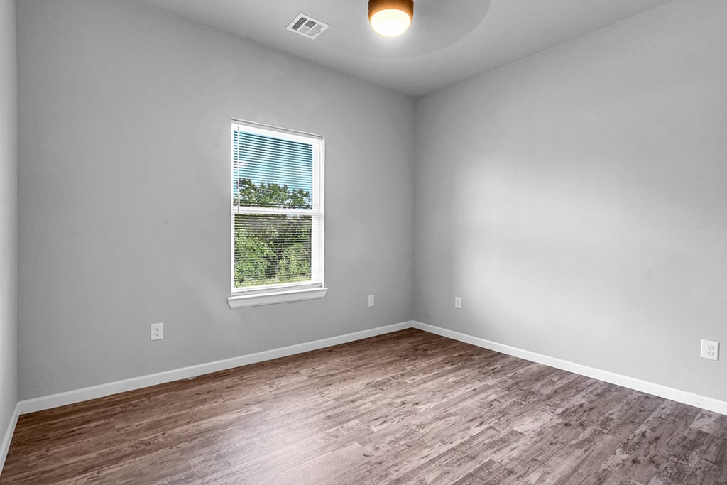 A room with a window and wooden flooring.