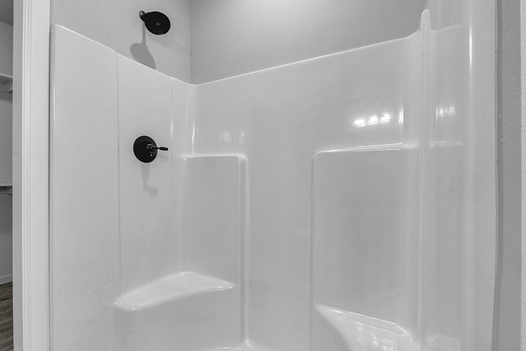 A white shower stall with a black handle.