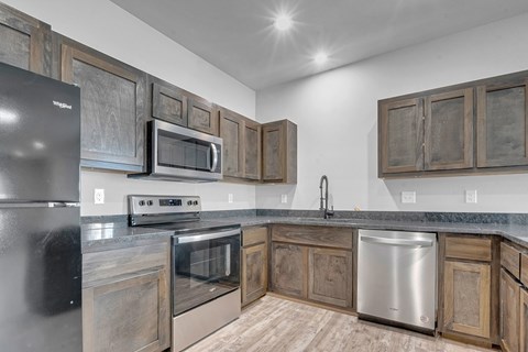 A kitchen with a black refrigerator and wooden cabinets.