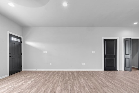 A room with wooden flooring and two doors.