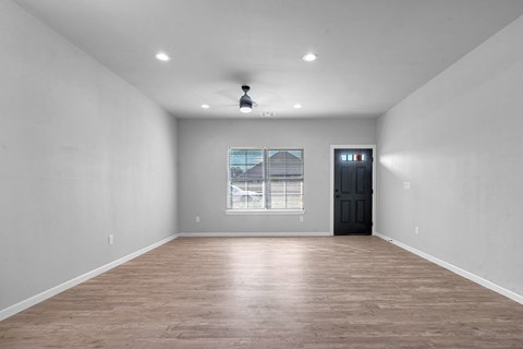 A room with a black door and a window with blinds.