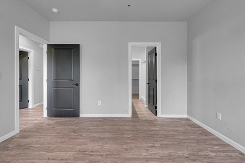 A room with a grey fridge and wooden flooring.