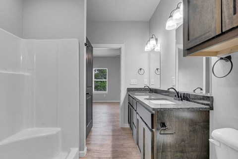 A bathroom with a white tub and a wooden vanity.