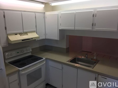 A kitchen with white cabinets and a stove top oven.