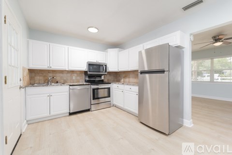 A kitchen with white cabinets and a stainless steel refrigerator.