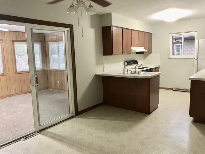 A kitchen with a refrigerator, sink, and cabinets.