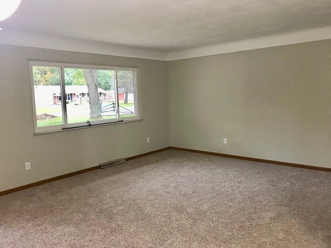 A room with a carpeted floor and a window.