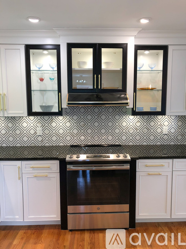 A kitchen with black and white cabinets and a patterned backsplash.