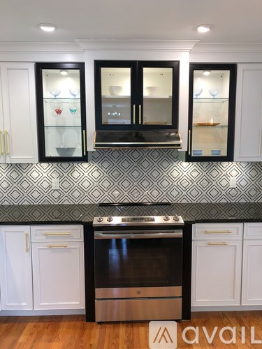 A kitchen with black and white cabinets and a patterned backsplash.