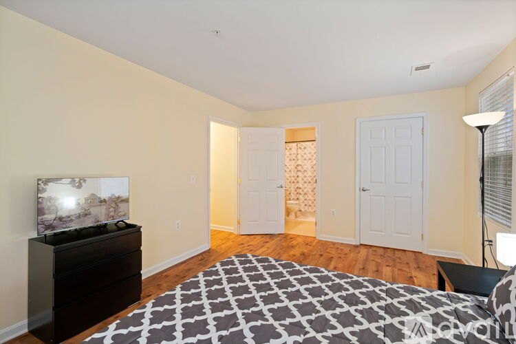 A bedroom with a large bed and a television on a dresser.