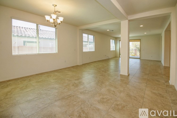 A spacious room with tiled flooring and a chandelier.