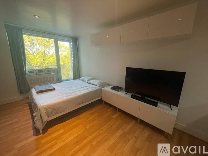 A bedroom with a bed, a television, and a window.