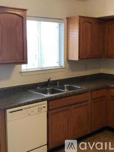 A kitchen with wooden cabinets and a white dishwasher.