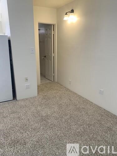 A hallway with a carpeted floor and a light on the wall.