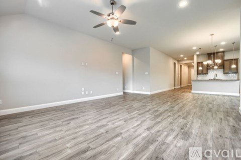 A spacious room with a ceiling fan and wooden flooring.