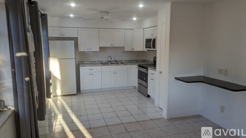 A kitchen with white cabinets and a black countertop.
