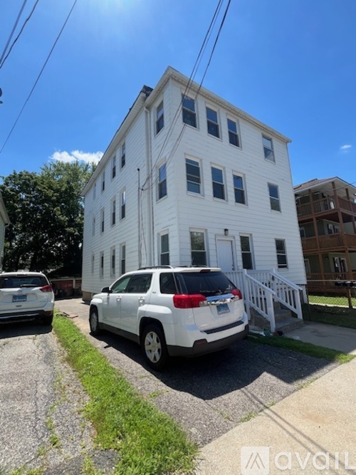 A white two-story building with a car parked in front.