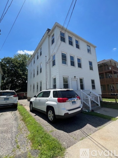 A white two-story building with a car parked in front.