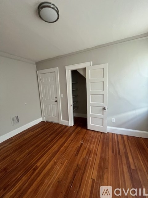 A room with a white door and a wooden floor.