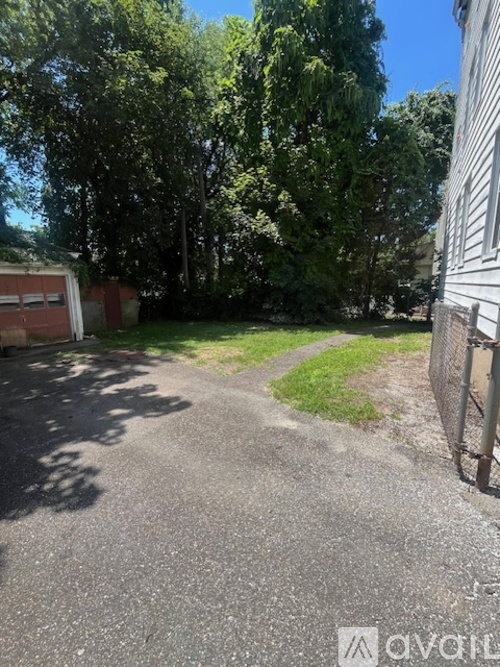 A backyard with a paved area, a fence, and trees.