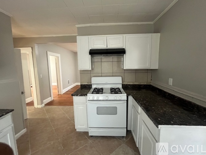 A kitchen with a white stove top oven and black countertops.