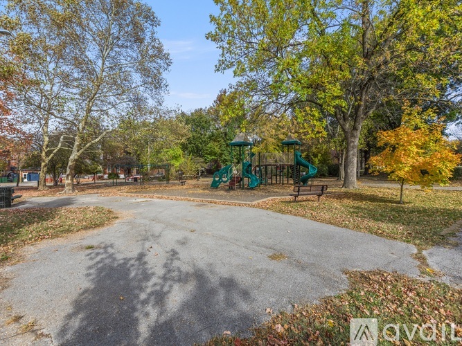 A playground with a slide and a tree with orange leaves.