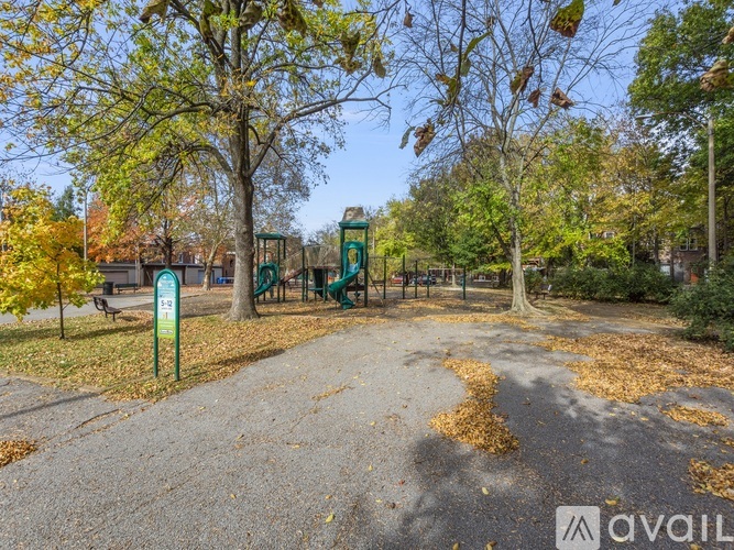 A park with a playground and fallen leaves on the ground.