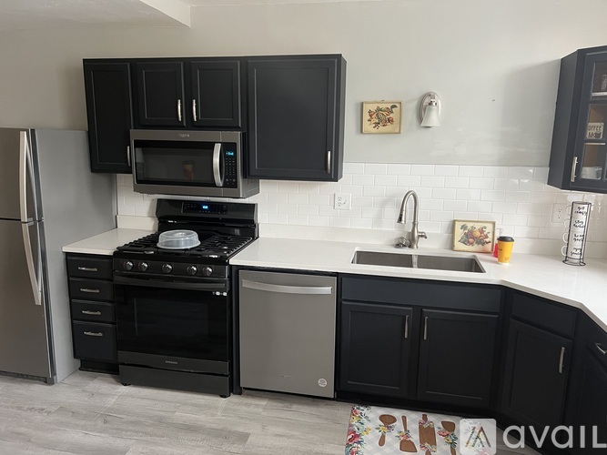 A kitchen with black cabinets and a white countertop.