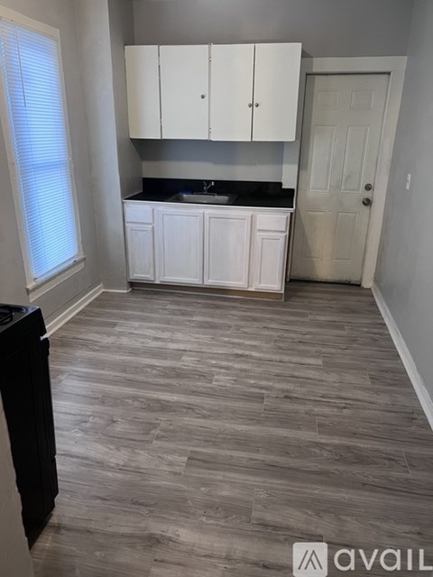 A kitchen with white cabinets and a black countertop.