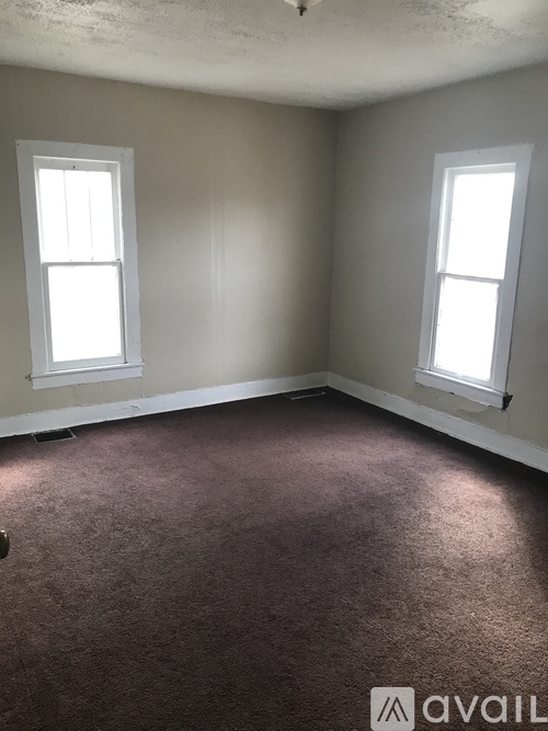 A room with two windows and carpeted floor.